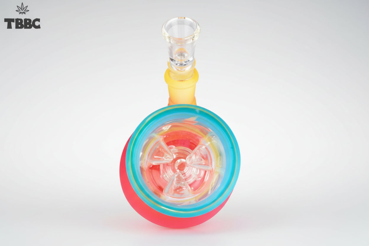 A colorful glass percolator ice bong with a clear base and multicolored upper part, featuring ice cubes inside and a blue lid. Instant delivery delhi ncr, exporter for quality glass bongs india