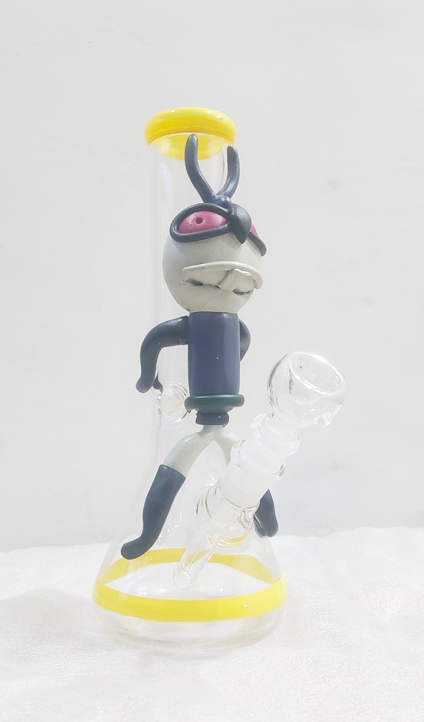 Animated character figurine with a white background, Close-up of a Trippy acid boy glass dick bong with yellow and black parts on a white background, instant delivery in delhi ncr, pan india smoking accessories brand tbbc theboomboxclub