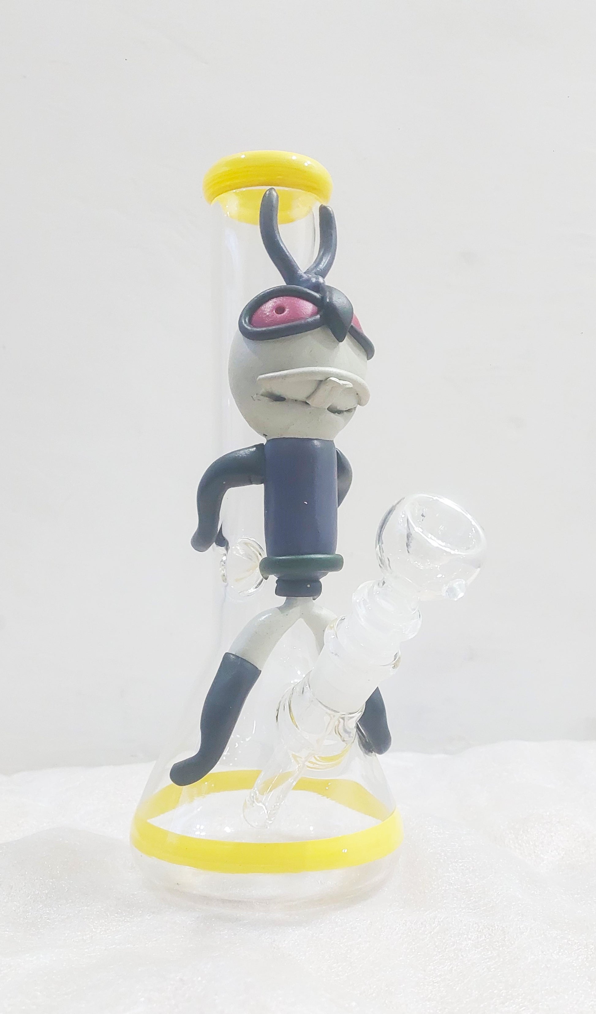 Animated character figurine with a white background, Close-up of a Trippy acid boy glass dick bong with yellow and black parts on a white background, instant delivery in delhi ncr, pan india smoking accessories brand tbbc theboomboxclub