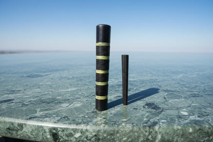 The image shows a black chillum with green rings, along with its lid.