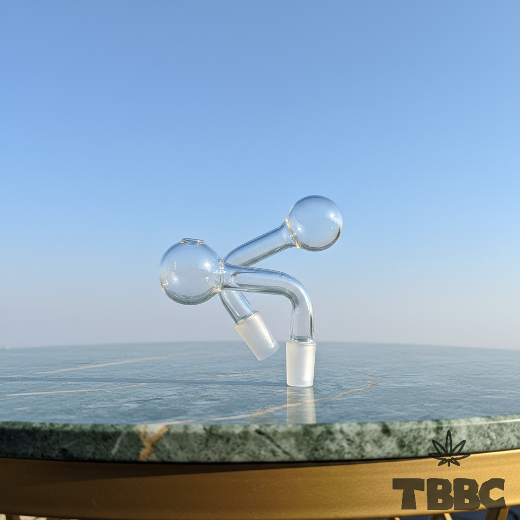 Two clear glass oil pipe attachments with curved necks and 14mm male joints on marble with a sky background