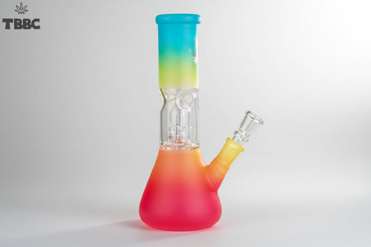 A colorful glass percolator ice bong with a clear base and multicolored upper part, featuring ice cubes inside and a blue lid. Instant delivery delhi ncr, exporter for quality glass bongs india