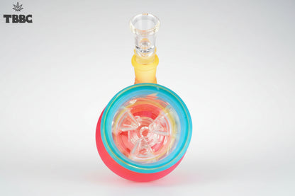 A colorful glass percolator ice bong with a clear base and multicolored upper part, featuring ice cubes inside and a blue lid. Instant delivery delhi ncr, exporter for quality glass bongs india