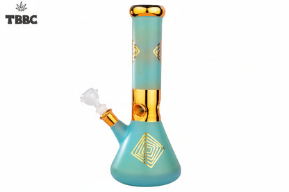 A blue glass bong with gold accents and geometric patterns, featuring a thick base and a narrow top, with a small amount of white smoke rising from the top. aladin-12-inch-heavy-ice-bong