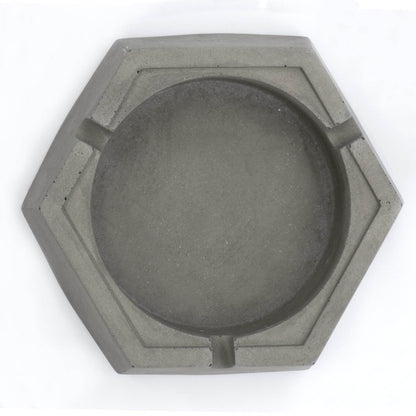 A dark, concrete ashtray with a geometric hexagonal shape, featuring a smoker holding a cigarette.hexagon greyt dankest stoner ashtrays, cement handcrafted home decor lifestyle ashtray,best cigarette_ashtray online nearby instant delivery