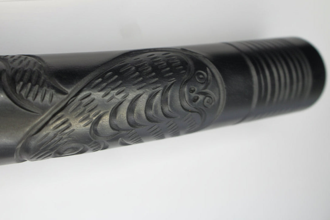 Decorative black metal object with engraved design on a white background