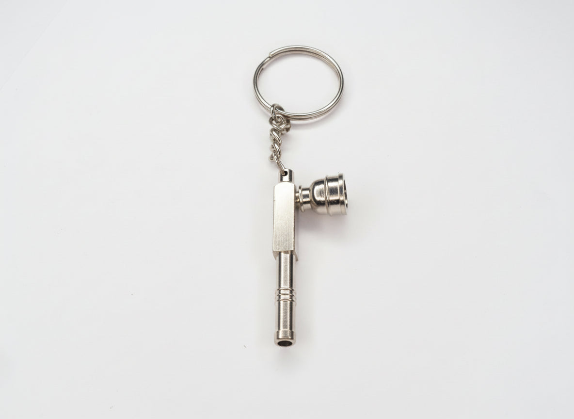 Metal key-shaped keychain on a plain background. Metal keychain with a tool-like design on a light gray background, small toking weed hand pipe key chain, easy to carry smoking accessory online instant delivery, best one hitter for weed stoners 420 lifestyle peace. tbbc, one hitter for weed 