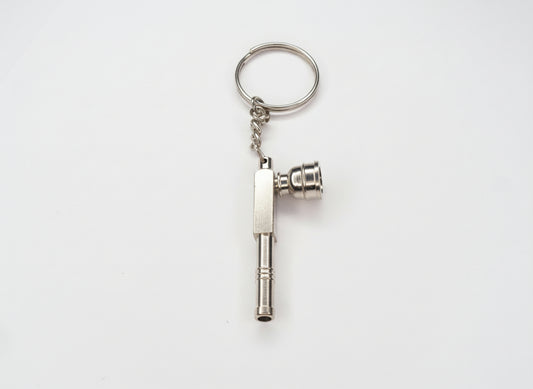 Metal key-shaped keychain on a plain background. Metal keychain with a tool-like design on a light gray background, small toking weed hand pipe key chain, easy to carry smoking accessory online instant delivery, best one hitter for weed stoners 420 lifestyle peace. tbbc, one hitter for weed 