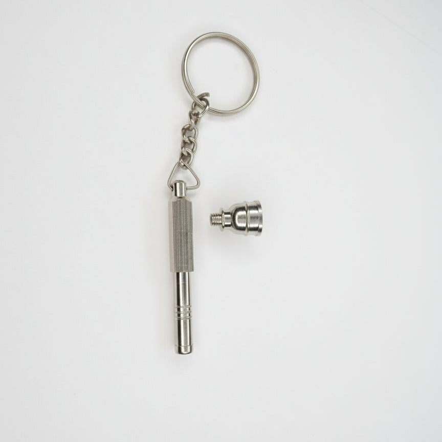 Metal keychain with a small attached component on a light gray, Metal key-shaped keychain on a plain background. Metal keychain with a tool-like design on a light gray background, small toking weed hand pipe key chain, easy to carry smoking accessory online instant delivery, best one hitter for weed stoners 420 lifestyle peace. tbbc, one hitter for weed  background