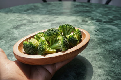 TBBC Wooden Rolling Tray side view - showing raised edges and natural wood grain with some veggies inside for crushing or grinding