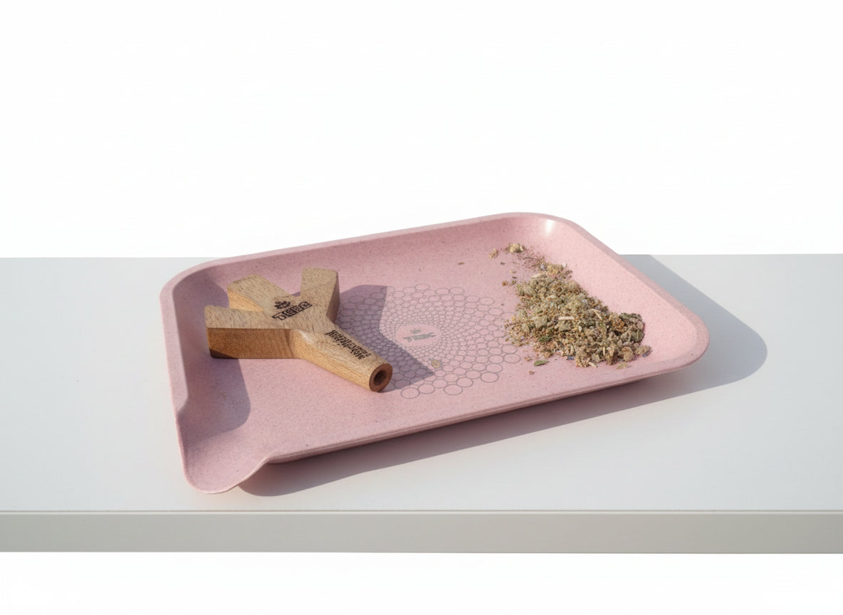 Pink tray with trident joint holder, rolled joint, and herbal mixture buds on a tbbc rose pink rolling tray