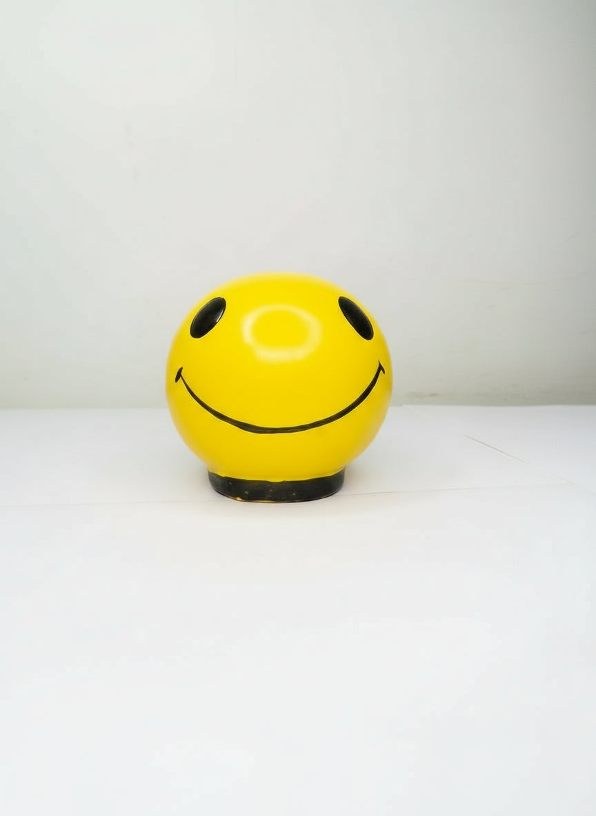 Yellow ball with a smiley face design attached to a white wall.
