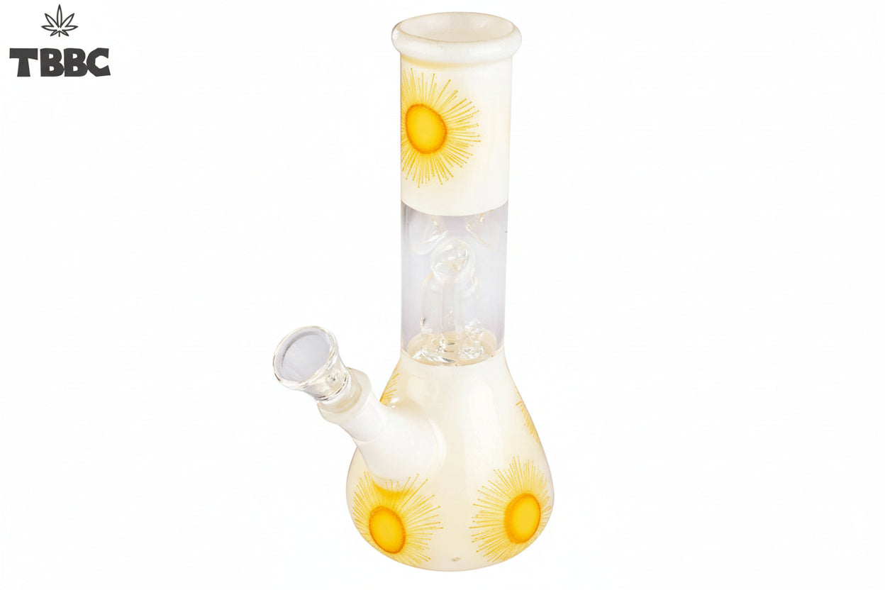 A beige-colored glass bong with a sunburst pattern, featuring yellow and orange hues, and ice spikes on the side, side view